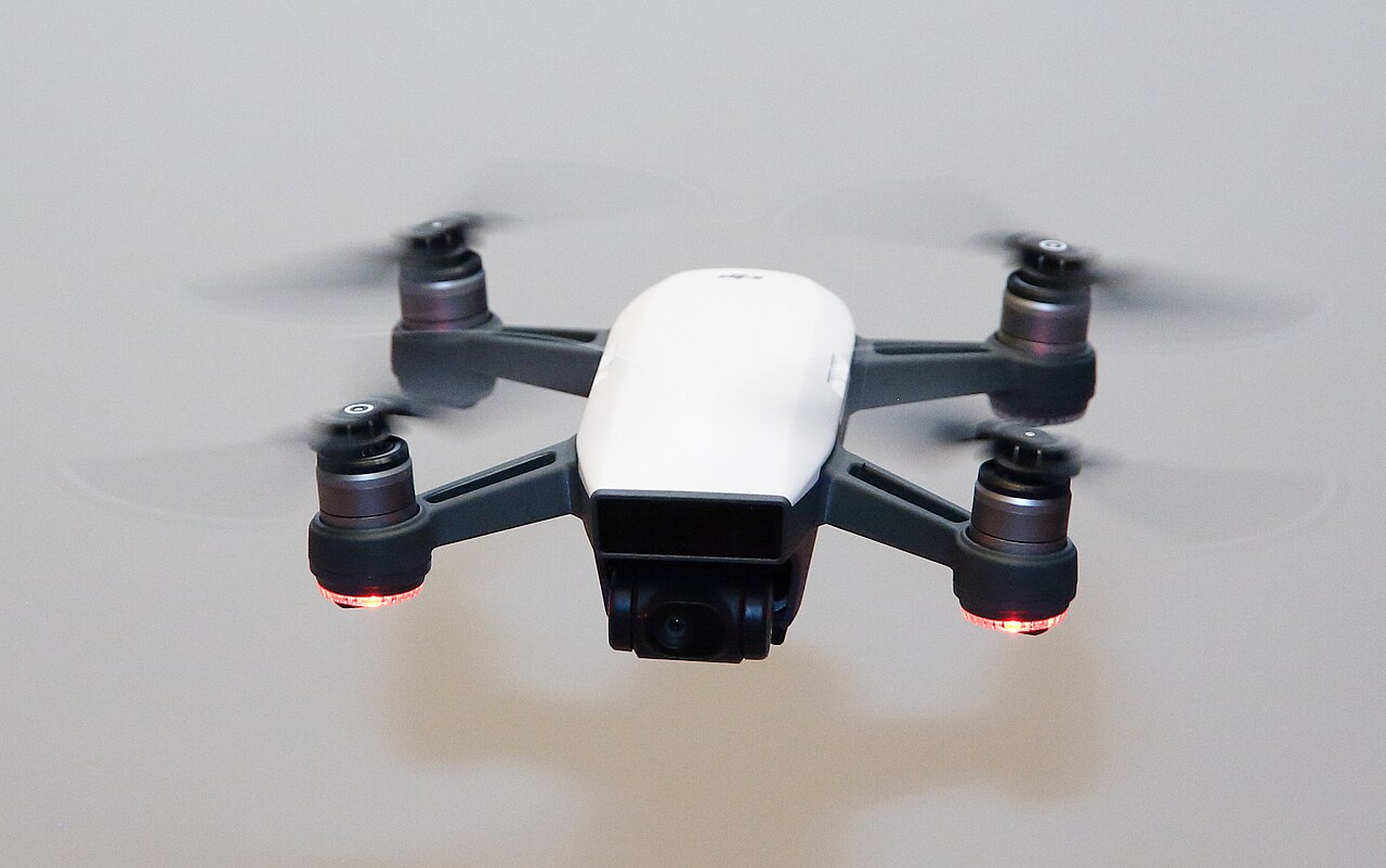 Front view of a small DJI Spark quadcopter hovering in flight.